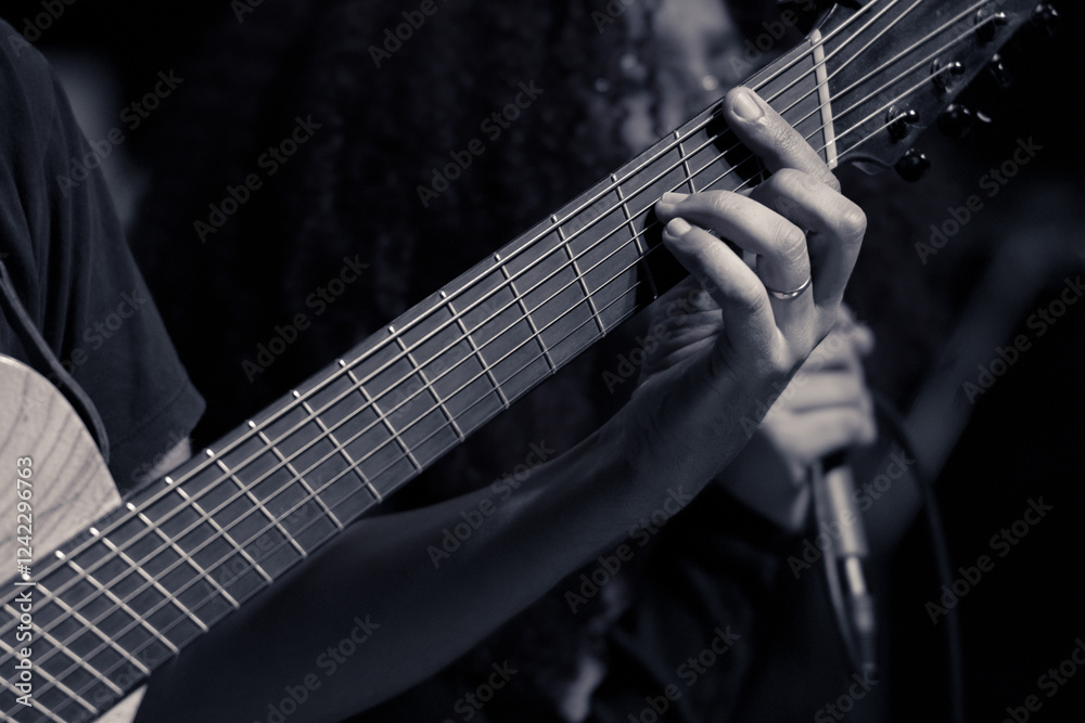 Close-up of guitarist’s hand playing the fretboard at a live performance. Close-up of guitarist’s hand playing the fretboard at a live performance.