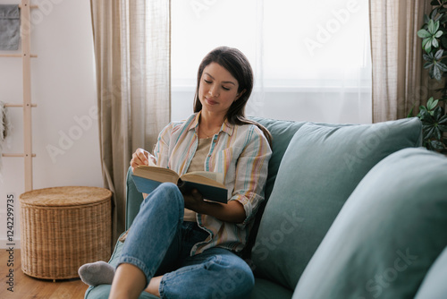 Woman Relaxing On Sofa Reading a Book in Cozy Living Room photo