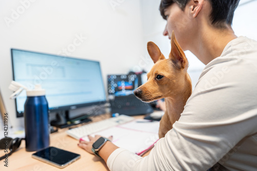 Woman working from home holding her small dog in her arms photo