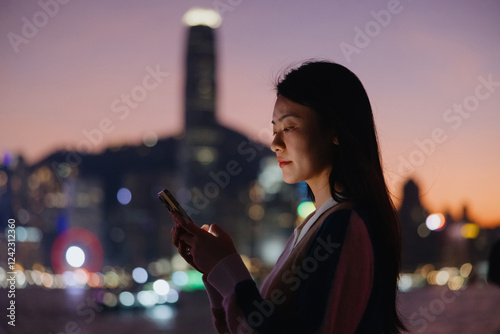 Woman Using Smartphone with City Lights at Dusk