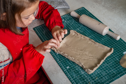 Child molds a plate from clay at an art school class photo