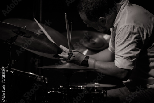 Drummer playing at jazz concert, focused on drumsticks.