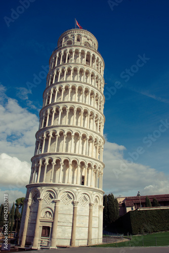 The iconic Leaning Tower of Pisa under a clear blue sky. The tower’s distinct tilt and intricate white marble architecture are prominently featured, symbolizing a historic marvel. photo