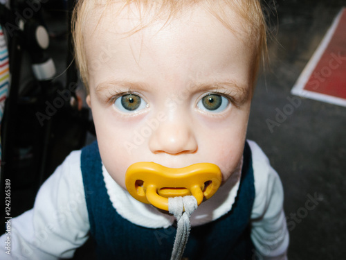 UGC Baby girl with pacifier looking up with big eyes photo