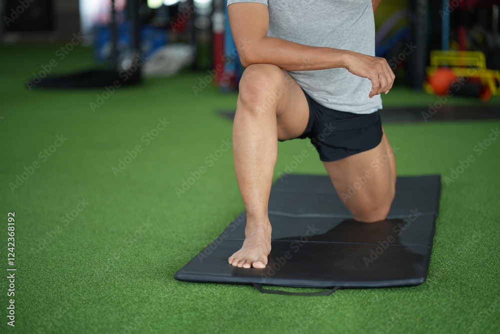 Naklejka premium Asian man stretching while in gym.