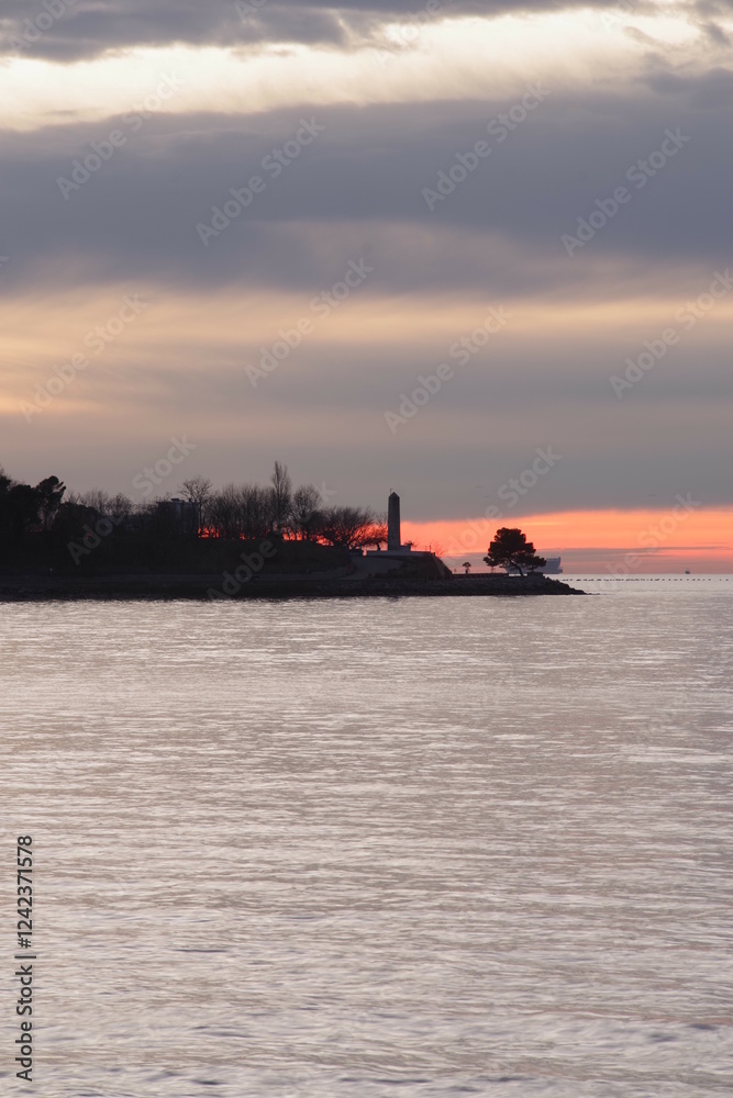 Lighthouse is on a rocky shoreline with a calm ocean Lighthouse is on a rocky shoreline with a calm ocean