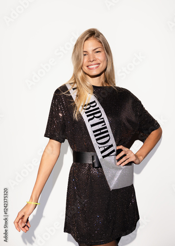 Cheerful woman celebrating birthday with a smile and sash