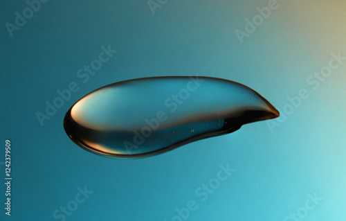 Droplet of fluid gel on blue and yellow gradient backdrop.