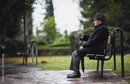 Senior man sitting on a bench in a peaceful park setting photo