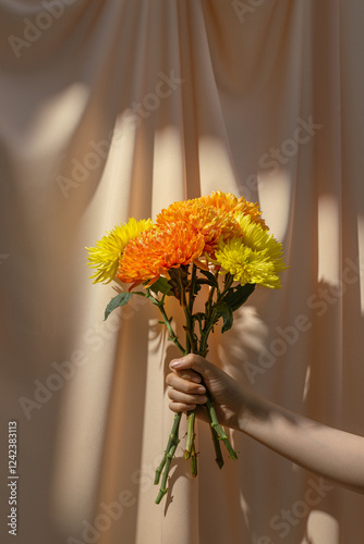 Hand Holding Bright Bouquet Against Neutral Background photo