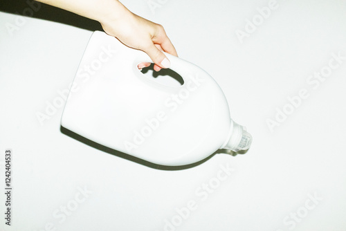 Hand holding a plastic cleaning detergent bottle and hard direct flash photo