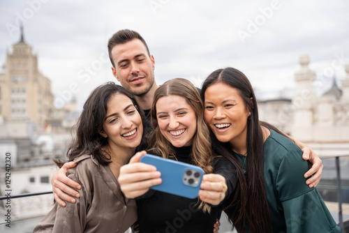 Group of smiling friends taking selfie on rooftop in madrid, spain photo