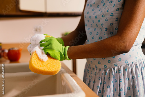 Woman squishing sponge over sink photo