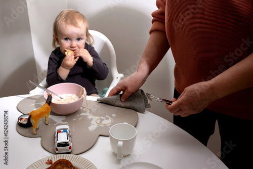 Grandma is cleaning the table where a little girl is eating. photo