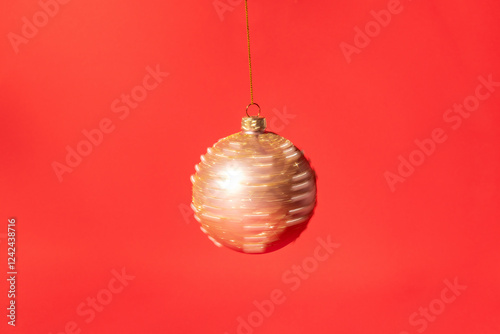 A decorative blurry golden ornament hanging on a bright red background