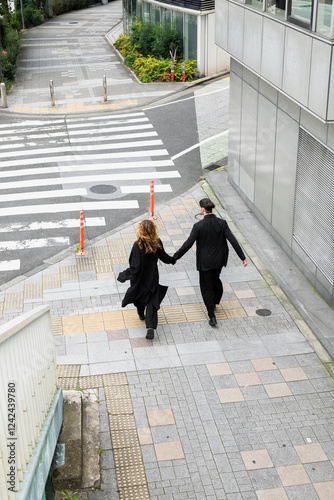 Couple walking hand-in-hand near urban zebra crossing photo