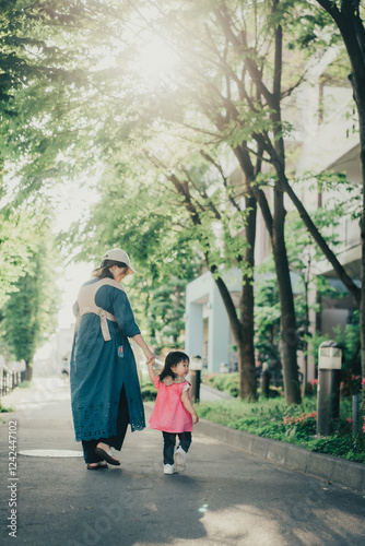 緑の小道を歩く赤ちゃんを抱っこしたお母さんと女の子