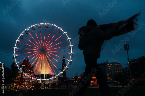 Silhouette of person with Ferris wheel and Christmas lights at n photo