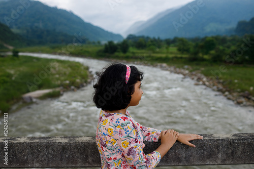 Young girl enjoying scenic views of hills and river photo