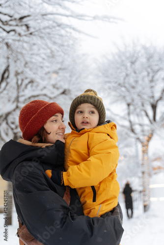 Mother holding her child in a snowy park with festive lights. photo