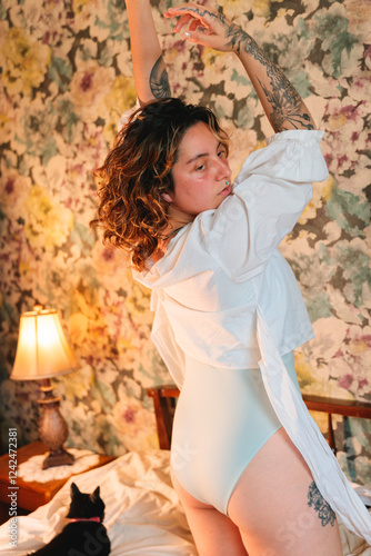 Young woman raising hands in bedroom photo