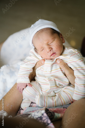 Newborn baby sleeping peacefully on mother's lap after photo