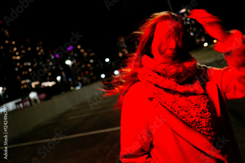  Woman in red light with hair blowing in wind, motion-blurred
 photo