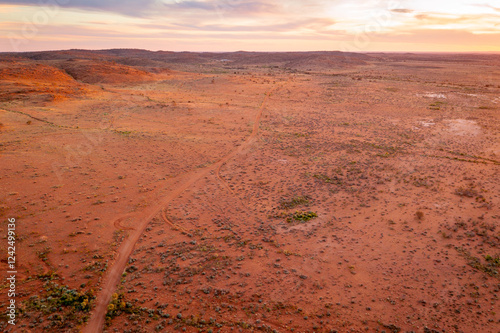 Remote dirt road through outback landscape at sunset photo