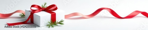 White gift box wrapped in a long red ribbon with sprigs of greenery, white, gift wrap