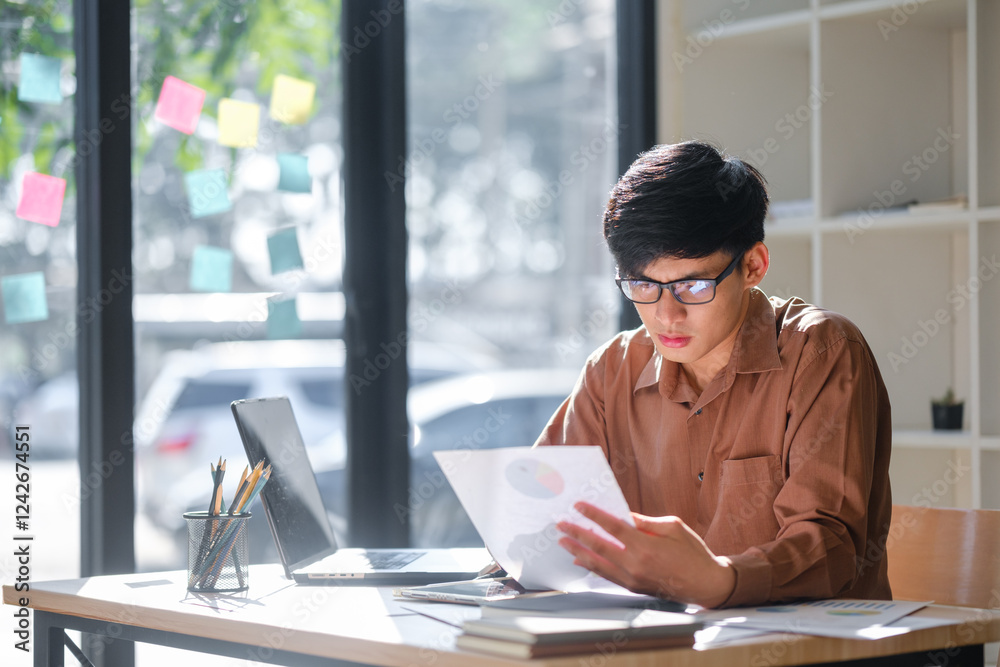 Young businessman analyzing financial data and market trends for investment decisions Young businessman analyzing financial data and market trends for investment decisions