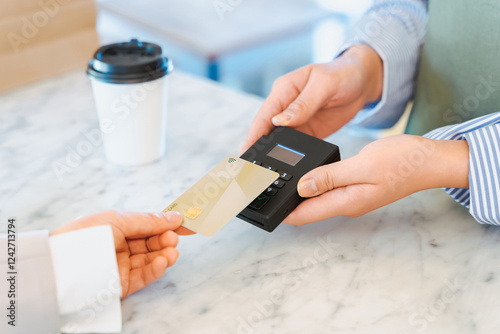 飲食店での買い物の支払いをクレジットカードのタッチ決済で行う女性の手元