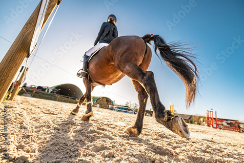 Spectaculaire contre-plongée d'un cavalier et de son cheval en plein mouvement sur un terrain de compétition équestre.