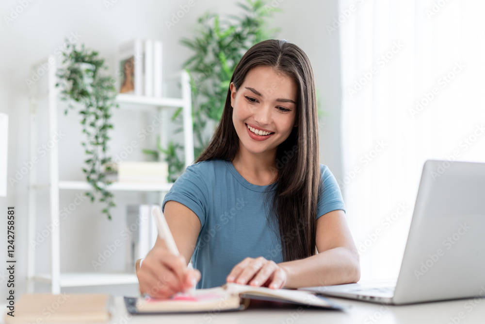 Asian attractive woman taking notes on book while learning from home. Asian attractive woman taking notes on book while learning from home.