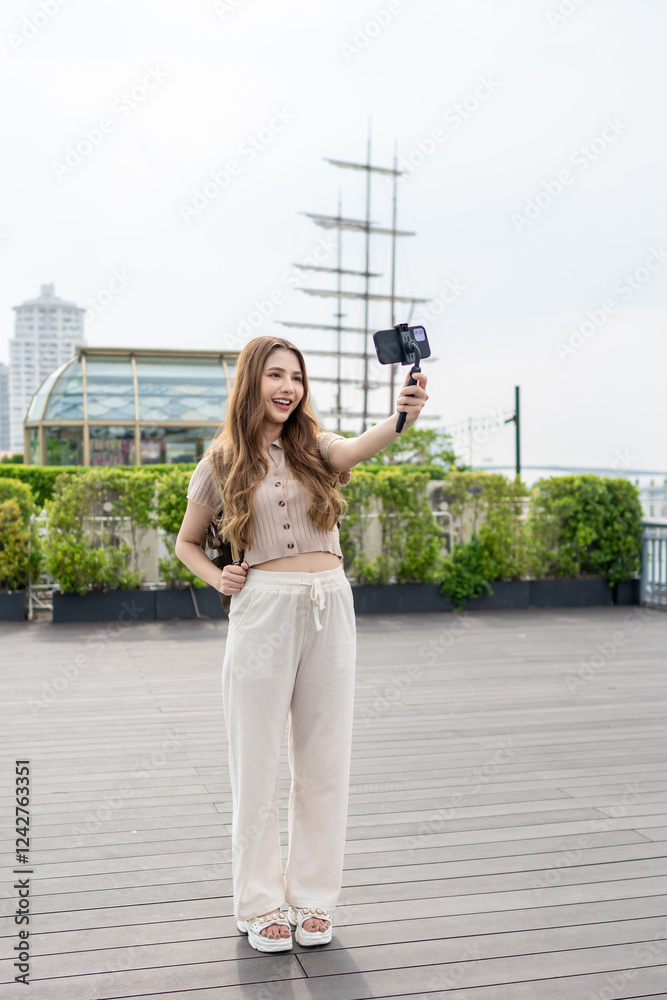 Fototapeta premium Asian beautiful woman backpacker taking a selfies outdoors in the city. 