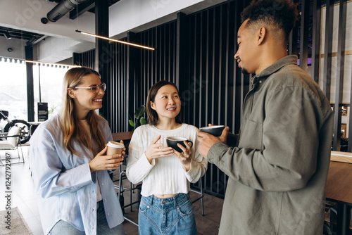 Multi-ethnic colleagues enjoying coffee break in modern office