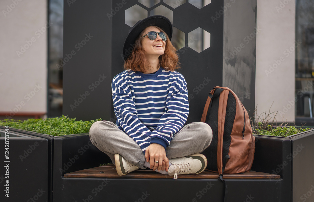 Smiling young woman in sunglasses sitting on a bench.Smiling young woman sitting on a bench.
