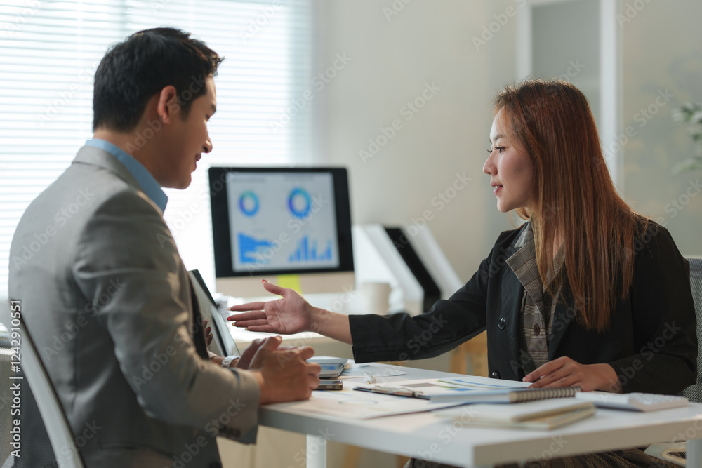 Two business colleagues are having a discussion in a modern office, analyzing charts and data displayed on a computer screen, engaging in collaborative problem-solving and strategic planning Two business colleagues are having a discussion in a modern office, analyzing charts and data displayed on a computer screen, engaging in collaborative problem-solving and strategic planning