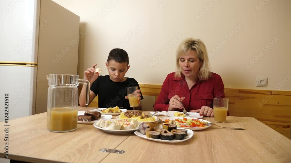 Mother and son sit at the festive table and enjoy delicious food. We celebrate at home. Mother and son sit at the festive table and enjoy delicious food. We celebrate at home.