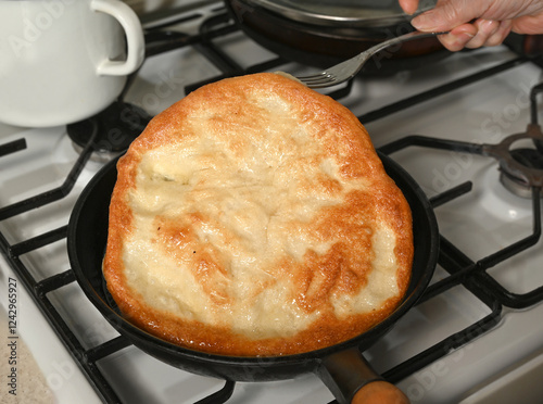 Obraz na płótnie Freshly cooked flatbread being lifted from a skillet on a stovetop in a home kitchen w salonie