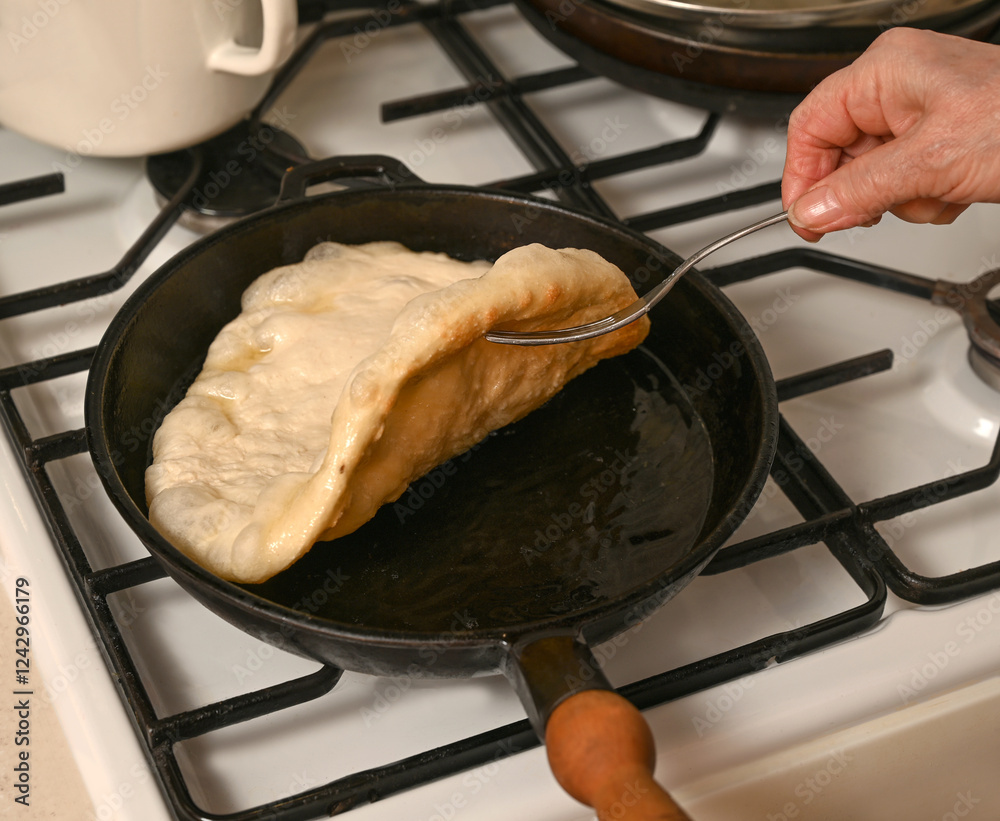 Freshly cooked dough being flipped in a frying pan over the stove during breakfast