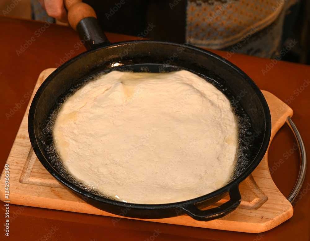 Homemade dough being cooked in a skillet on a wooden cutting board