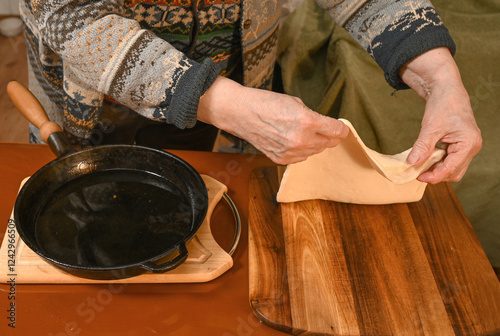 Obraz na płótnie Preparing dough for traditional cooking in a cozy kitchen setting with a cast iron skillet w salonie
