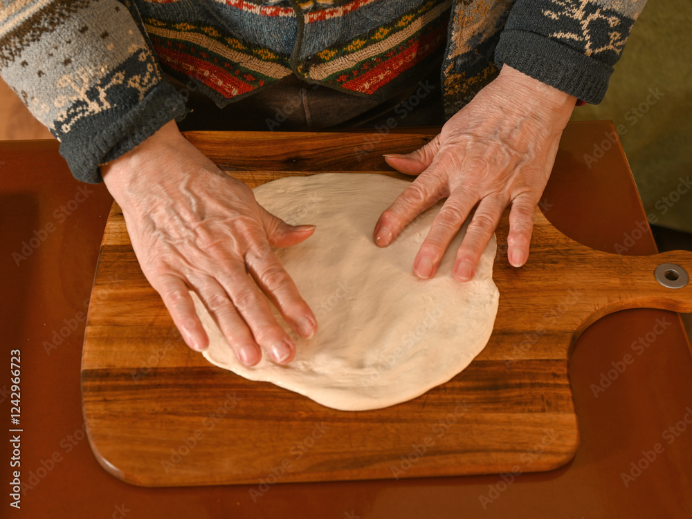 Hands shaping dough on a wooden board in a cozy kitchen during an afternoon baking session