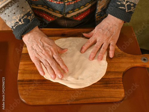 Obraz na płótnie Hands shaping dough on a wooden board in a cozy kitchen during an afternoon baking session w salonie
