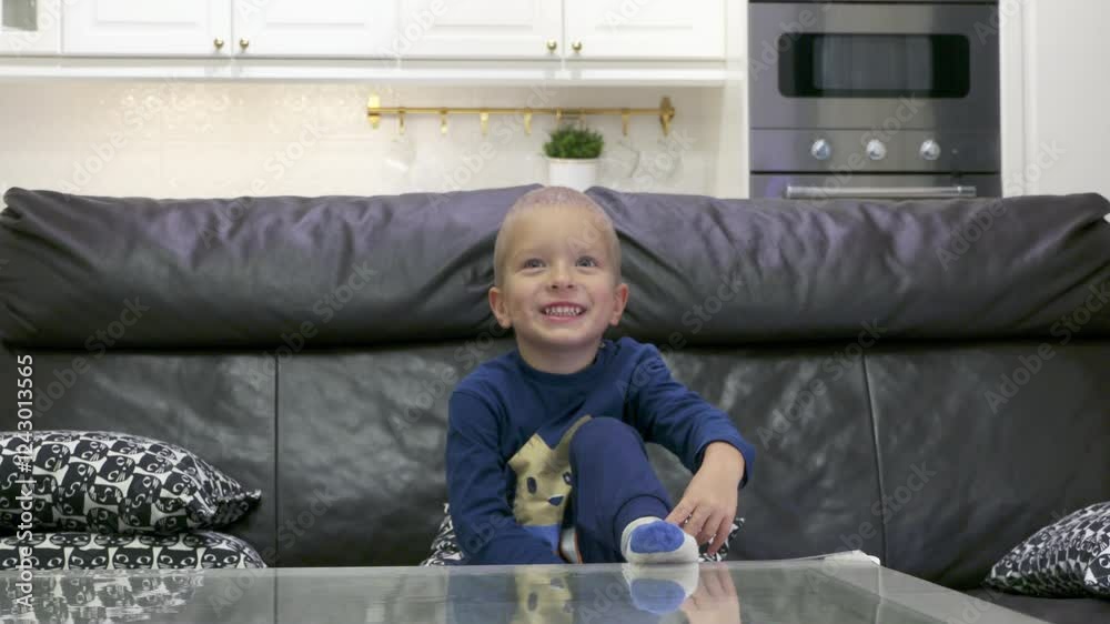 Excited child waiting for surprise. Happy little boy jumps up from the sofa smiling and raising his hands up in anticipation of a gift. Excited child waiting for surprise. Happy little boy jumps up from the sofa smiling and raising his hands up in anticipation of a gift.