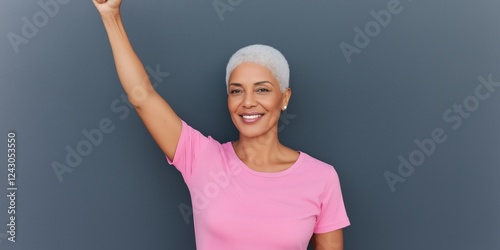 A woman in a pink shirt is holding her hand up in the air. She is smiling and she is happy