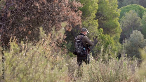 Hunter walking and aiming with shotgun in the woods