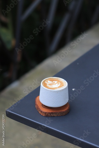 Coffee Cup Sits on Table Decorated Beautifully with Latte Art and Coaster in Cafe