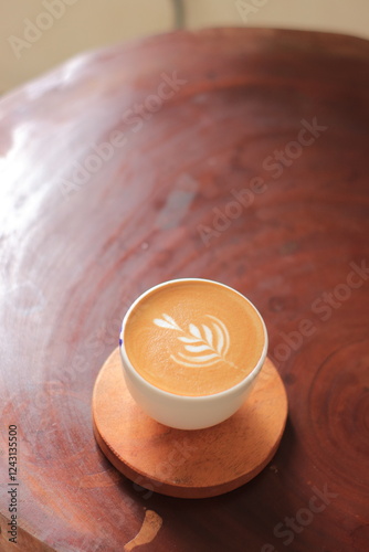 Coffee Cup Sits Beautifully on Wooden Coaster: A Cozy Cafe Experience with Latte Art