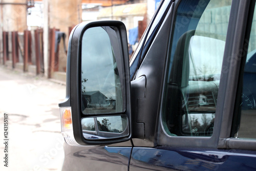 Cargo van side mirror with reflection in it. Black Rear-view mirror on a cargo van. Left external door car mirror.